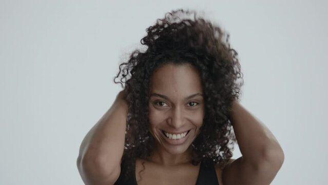 ECU Headshot portrait of beautiful 20s African-American Black female posing and doing silly faces against white background, smiling and laughing, no make-up, clean skin. Shot with ARRI Alexa Mini LF