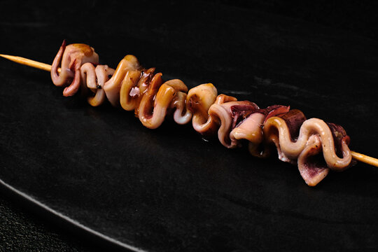 Japanese Seafood Skewers. Salmon fillet, on black plate on blavk concrete background. Pan Asian dish isolation. Kusiyaki seafood. Top view