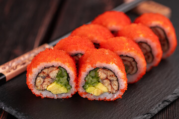 California sushi roll with eel, cucumber and tobiko caviar served on black board close-up - Japanese food