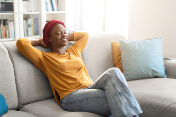 Relaxed black lady resting on couch at home