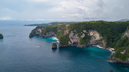 Beautiful coastline aerial view from Saren Cliff Point. Clear water and rocks with cloudy sky. Nusa Penida, Indonesia.
