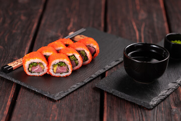 California sushi roll with tuna, avocado cucumber and tobiko caviar served on black board close-up - Japanese food
