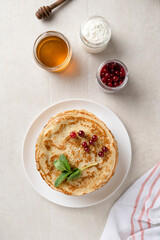 Stack of homemade pancakes served with honey and berries, top view