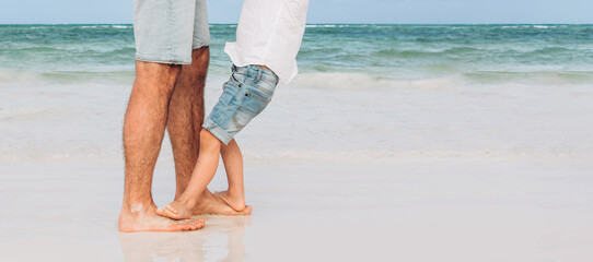 Father and son playing on the beach at the day time. Concept of friendly family
