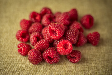 closeup of a bunch of healthy red raspberries on a brown linen tablecloth