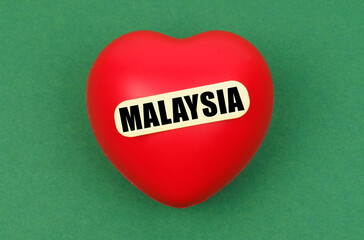 On a green surface lies a red heart with the inscription - Malaysia