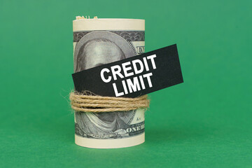 On a green surface, rolled dollars with a black sign that says - CREDIT LIMIT