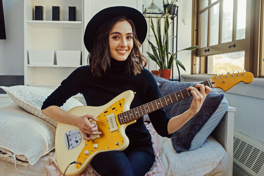 woman playing electric guitar at home