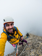 boy climbing, taking a portrait smiling on the mountain, with fog