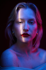 Portrait of a serious young blond woman isolated on magenta background. Viva magenta.