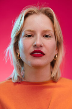 Portrait of a young blond woman in yellow sweatshirt isolated on magenta background. Viva magenta.