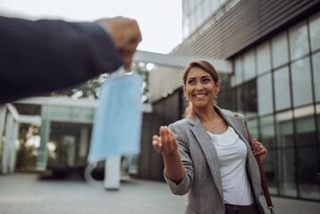 Man giving face mask to business woman