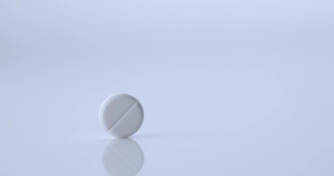 white tablet rolls through the frame, slow motion video
