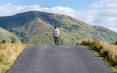 A graceful woman walking the road to the mountains in Connemara, County Galway, Ireland