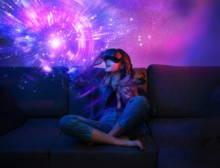 Naklejka premium Teenager girl touching helmet and wearing virtual reality headset. She is sitting on couch with dog pet. Future digital vr technology and entertainment. Space exploration with reality glasses
