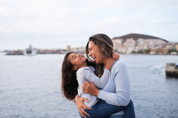 Mother and little daughter hugging while walking by the sea - motherhood, happiness and love concept