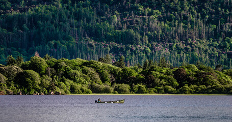 A lone fisherman fishing in a  Lough Leane from a boat in Killarney National Park, Ring of Kerry,...