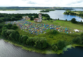 Tents on the peninsula near the lake. Rest with a tent in nature. Lots of molasses during mass camping on the lake. Campground at lakeside, aerial view. 