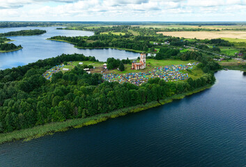 Fototapeta na wymiar Tents on the peninsula near the lake. Rest with a tent in nature. Lots of molasses during mass camping on the lake. Campground at lakeside, aerial view. 