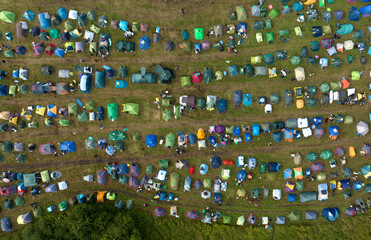 Obraz premium Tents camp, top view. Rest with a tent in nature. Mass camping with colorful tents, aerial view. Tent, drone view.
