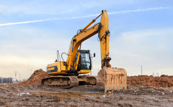 Excavator dig ground at construction site. Dig foundation. Construction of residential buildings, renovation program. Earthmover on groundwork. Building construction. Excavator on earthmoving.