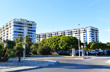 Facade of a building. Residential building with balconies. Buildings and hotel apartments. Facade of building with window.  City street, road traffic, cars, people and buildings. Urban architecture.