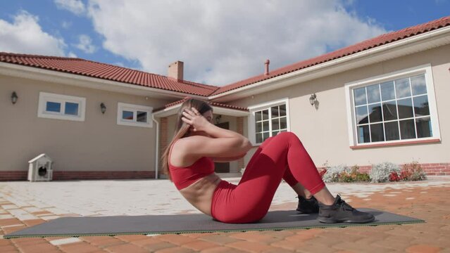 Woman lies on her back with the knees bent and feet planted. Girl crosses her arms behind the head, raising the torso using her abs. High quality 4k footage