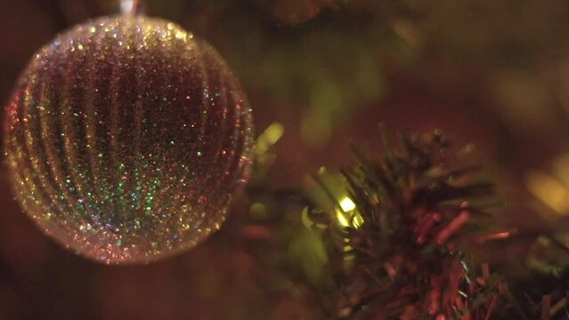 Christmas ornament hanging from Christmas tree with lights in background.