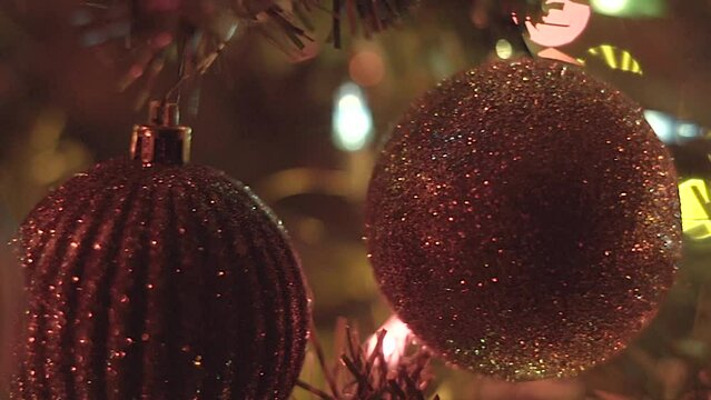 Christmas ornaments hanging on tree, macro closeup of decorations with lights in background 
