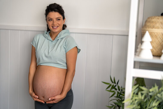 Photo of a beautiful pregnant woman who is expecting baby, indoors at home.