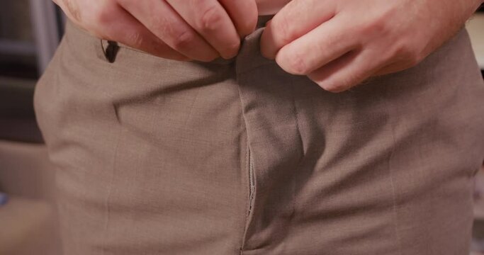 Male dressing up trousers on and zipping zipper, closeup