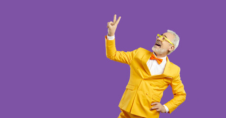 Portrait of cheerful cheery mustache bearded grey-haired man wearing elegant yellow blazer with bow tie showing double v-sign isolated over bright vivid shine vibrant purple color background. 