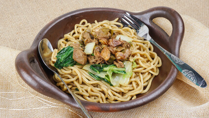 An indonesian chicken noodle with chicken broth in traditional wok. selective focus