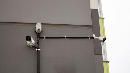 Surveillance cameras on the wall of a high-rise apartment building. Video equipment for security system control of the area on the street.