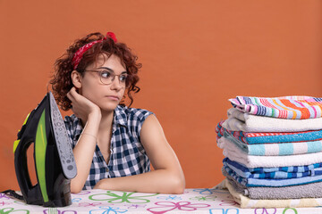 A girl with glasses glances at some ironed towels. Curly hair.
