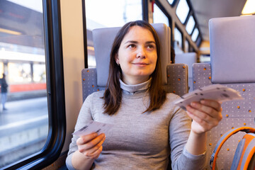 Woman showing tickets to attendant while traveling by train.