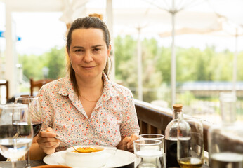 Portrait of woman spending time on open terrace of restaurant and eating traditional spanish gazpacho