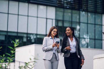 Two multiracial business woman meeting outside in front of the office building