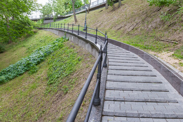 Obraz premium Paved path with railings on hillside in summer city park