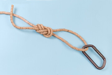 Carabiner in rope knot аigure-eight loop on blue background