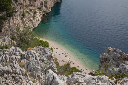 Scenic Nugal Beach-pebbly beach preferred by nudists-below a huge vertical rock wall towering above turquoise water at Gradac viewpoint with a stunning view to the coastline and Mount Biokovo, Croatia