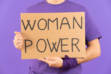Closeup of feminist activist holding billboard with woman power message isolated on purple...