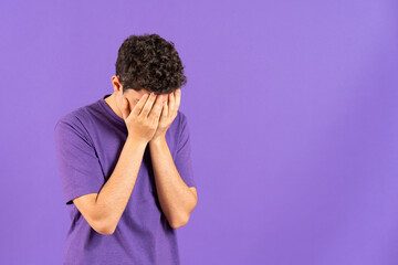 Sad hispanic boy hands on face isolated on purple background with copy space