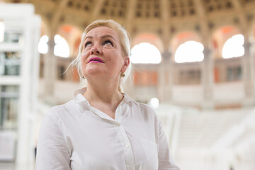 Closeup on attentive elegant senior woman wearing white blouse visiting museum