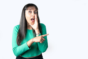 Surprised woman pointing finger to the side over white background with blank space for advertisement