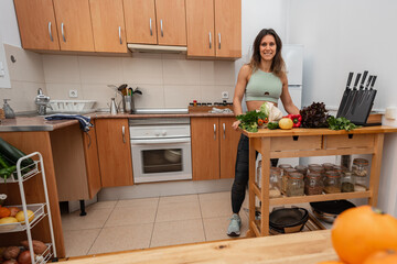 Athletic girl in sportswear with eco bag with vegetables in a kitchen. Vegan woman. Proper nutrition concept.