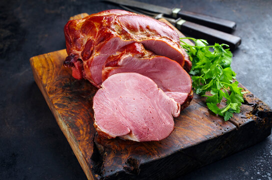 Traditionell gep&ouml;keltes und ger&auml;uchertes badisches Sch&auml;ufele von der Schweineschulter serviert geschmort mit Petersilie aufgeschnitten als close-up auf einem rustikalen Holz Schneidebrett 