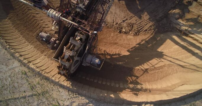 giant brown metal bucket wheel excavator ladles scoop overburden ground under bright summer sunlight upper view