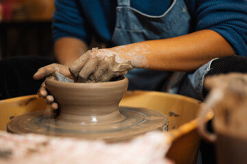 Fototapeta na wymiar Close up on skillful male hands making and sculpting pottery jar on potter’s wheel with tools and water in workshop, Creative and artwork, Handmade craft.