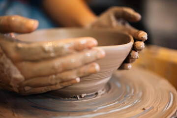 Fototapeta na wymiar Close up on skillful male hands making and sculpting pottery jar on potter’s wheel with tools and water in workshop, Creative and artwork, Handmade craft.